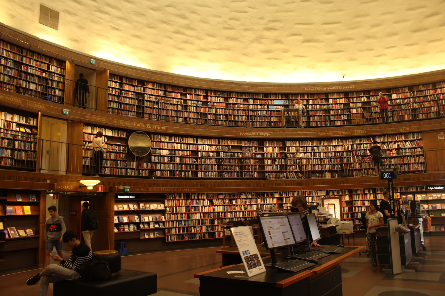 People browse books and use computers inside a circular library.