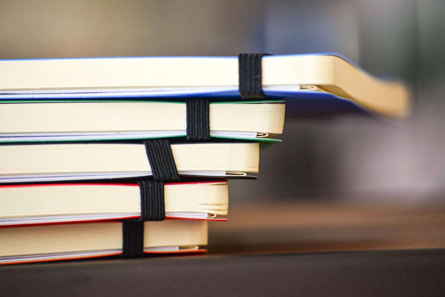 Stack of colorful notebooks secured with elastic bands.