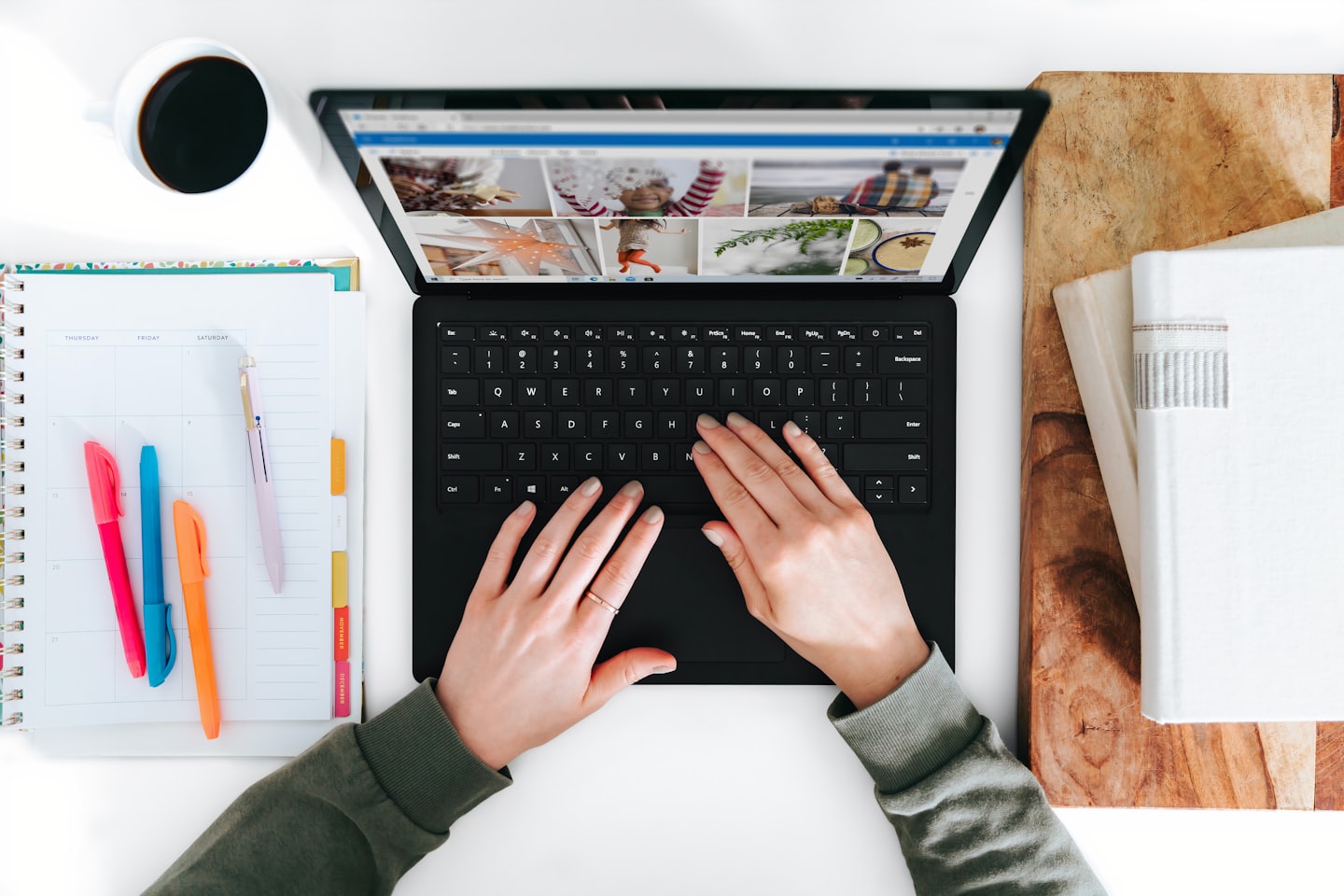 Hands typing on a laptop with office supplies on a desk.