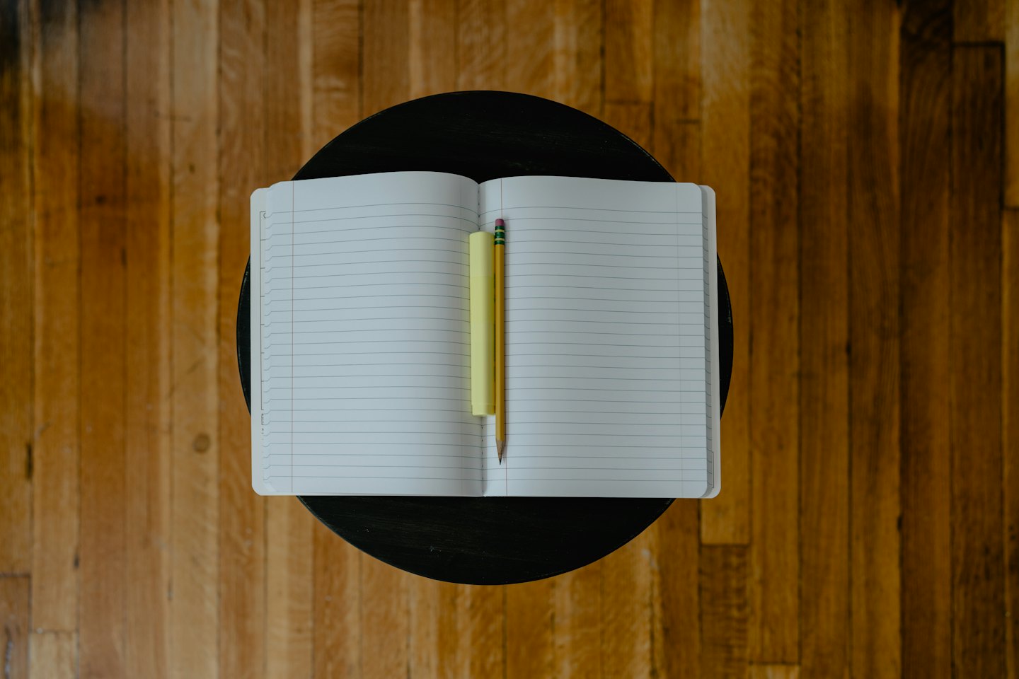 Notebook, pencil, and sticky notes on a round table.